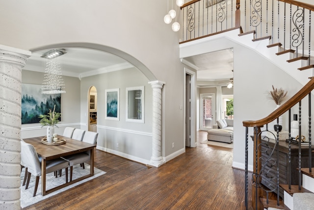 entryway with ceiling fan with notable chandelier, dark hardwood / wood-style floors, decorative columns, and ornamental molding