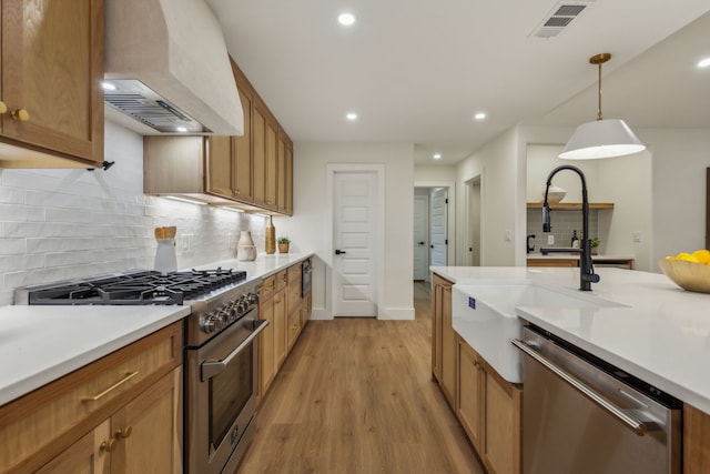 kitchen with sink, stainless steel appliances, light hardwood / wood-style flooring, pendant lighting, and custom exhaust hood