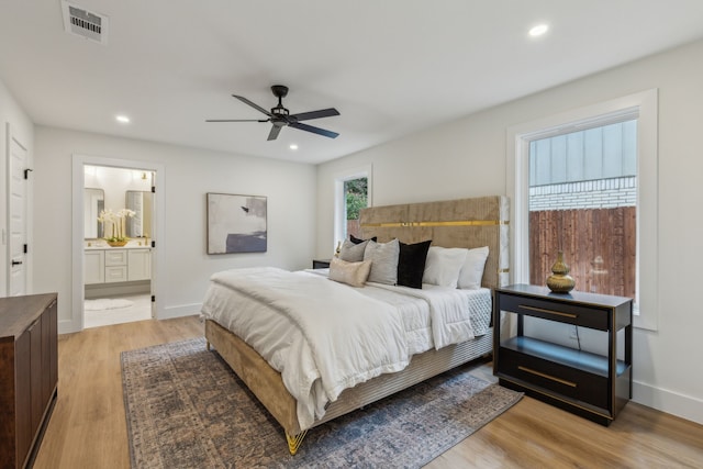 bedroom featuring ceiling fan, ensuite bathroom, and light wood-type flooring