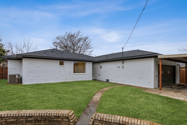 rear view of property featuring a garage, a lawn, and central air condition unit