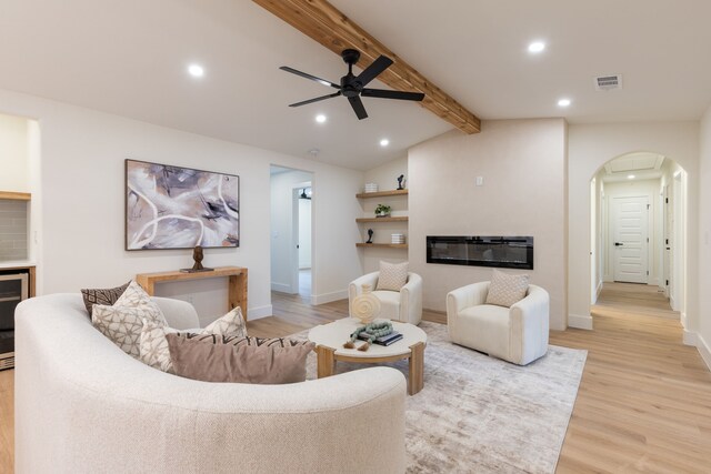 living room featuring lofted ceiling with beams, ceiling fan, and light wood-type flooring