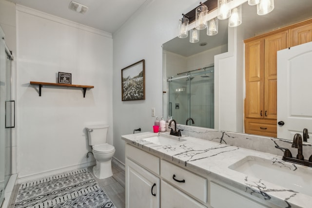 bathroom featuring toilet, vanity, crown molding, and a shower with shower door