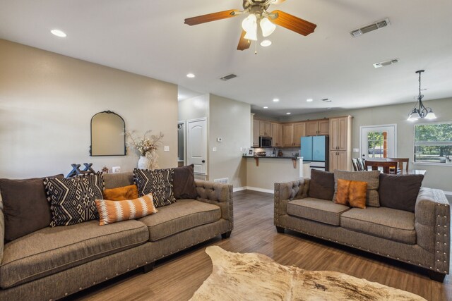 living room with ceiling fan with notable chandelier and hardwood / wood-style flooring