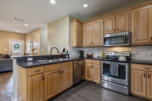 kitchen featuring kitchen peninsula, appliances with stainless steel finishes, backsplash, dark wood-type flooring, and sink