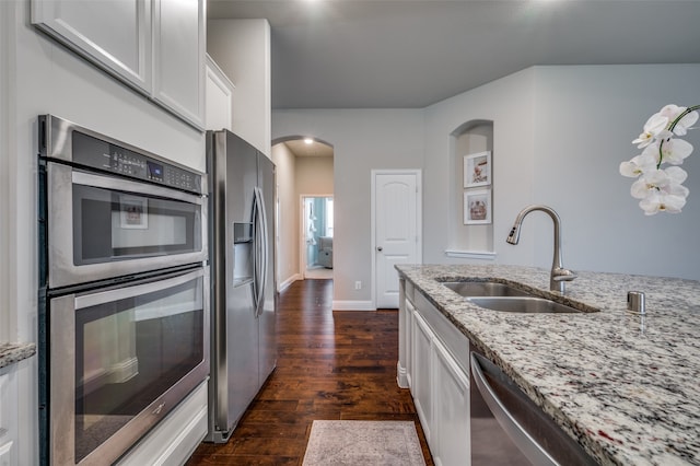 kitchen with white cabinetry, sink, light stone countertops, dark hardwood / wood-style flooring, and appliances with stainless steel finishes