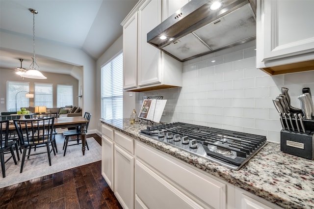 kitchen featuring dark hardwood / wood-style flooring, stainless steel gas cooktop, exhaust hood, white cabinetry, and hanging light fixtures