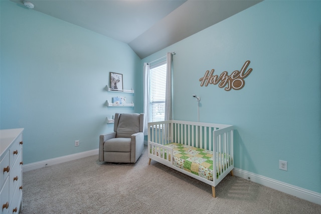 bedroom with lofted ceiling, a crib, and light carpet