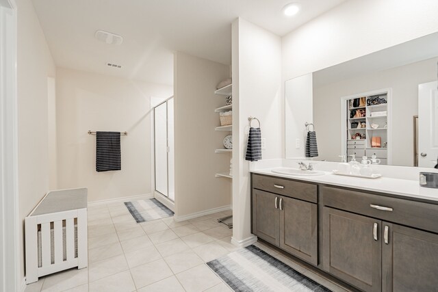 bathroom featuring tile patterned floors, built in features, vanity, and a shower with door