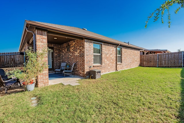 rear view of property with a lawn and a patio