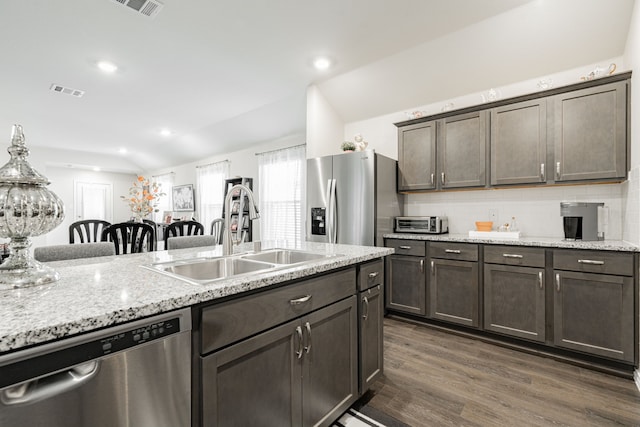 kitchen featuring sink, dark wood-type flooring, tasteful backsplash, vaulted ceiling, and appliances with stainless steel finishes