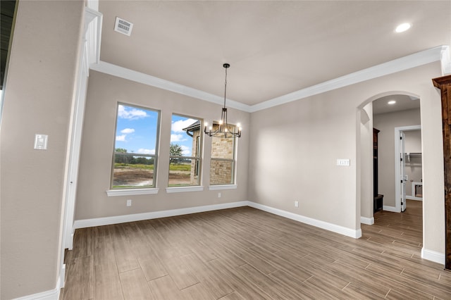 unfurnished dining area with crown molding, an inviting chandelier, and light wood-type flooring