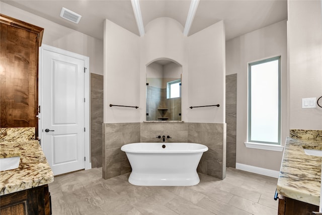 bathroom featuring vanity, lofted ceiling, a tub, and tile walls