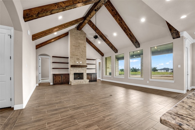 unfurnished living room with beam ceiling, a fireplace, a wealth of natural light, and hardwood / wood-style floors