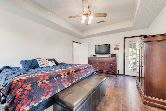 bedroom featuring access to exterior, dark hardwood / wood-style flooring, a textured ceiling, a tray ceiling, and ceiling fan