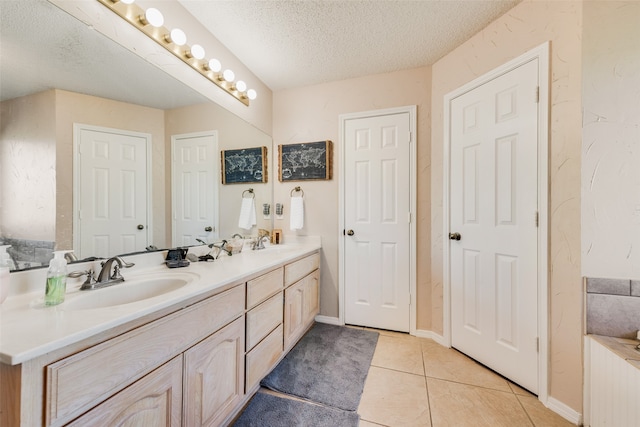 bathroom with tile patterned flooring, vanity, and a textured ceiling