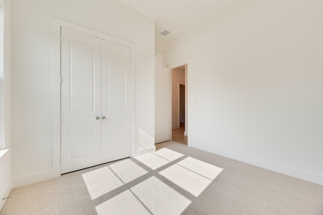unfurnished bedroom with light colored carpet, baseboards, visible vents, and a closet