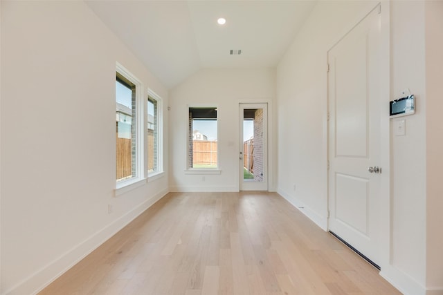 empty room featuring recessed lighting, baseboards, lofted ceiling, light wood-type flooring, and visible vents