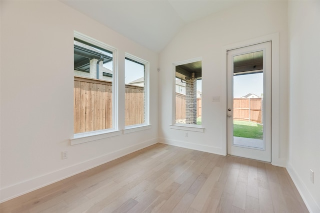 interior space featuring baseboards, light wood-style flooring, lofted ceiling, and a wealth of natural light