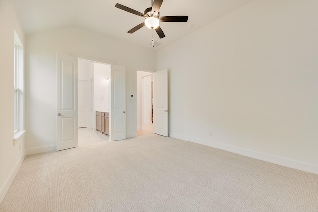 unfurnished bedroom with baseboards, ceiling fan, vaulted ceiling, and light carpet