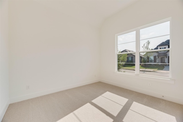 spare room featuring baseboards, light carpet, and lofted ceiling