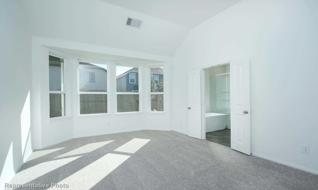 unfurnished bedroom featuring carpet, ensuite bathroom, and lofted ceiling