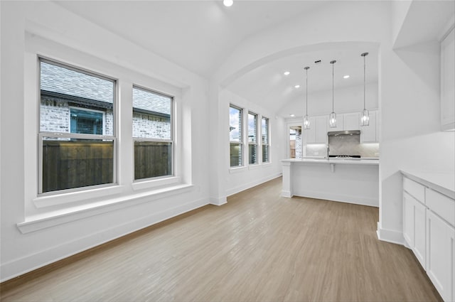 unfurnished living room with lofted ceiling, light wood-style flooring, baseboards, and recessed lighting