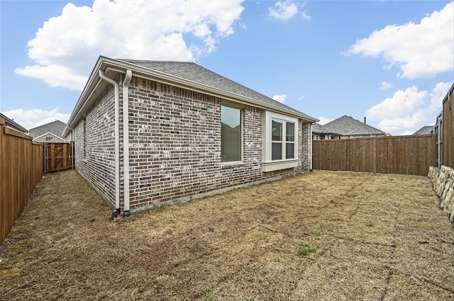 back of house with brick siding and a fenced backyard