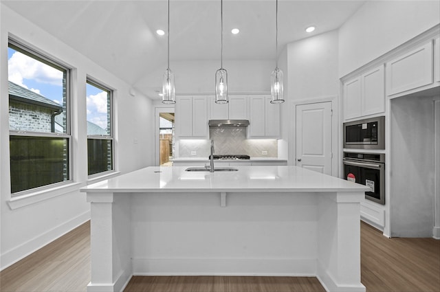 kitchen with built in microwave, white cabinets, stainless steel oven, and a sink