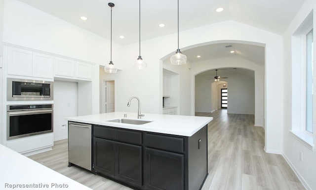 kitchen featuring ceiling fan, dishwasher, an island with sink, lofted ceiling, and decorative light fixtures