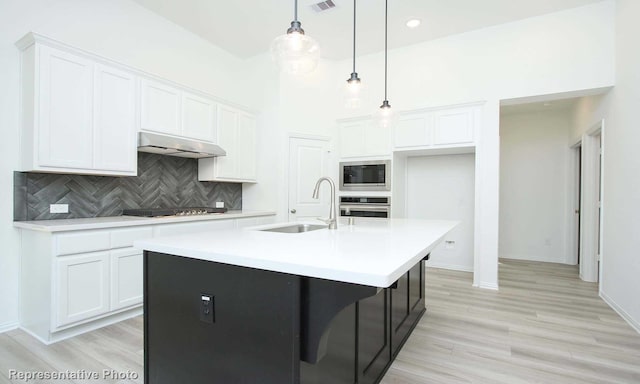 kitchen featuring stainless steel appliances, white cabinetry, a kitchen island with sink, and sink