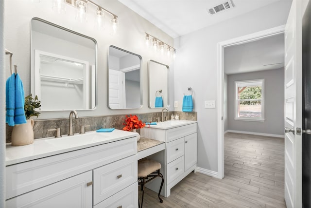 bathroom with backsplash, vanity, and wood-type flooring