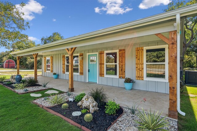 view of front of house with a front yard, a porch, and central AC unit