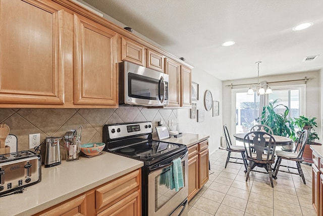 kitchen featuring appliances with stainless steel finishes, backsplash, light tile patterned floors, an inviting chandelier, and hanging light fixtures