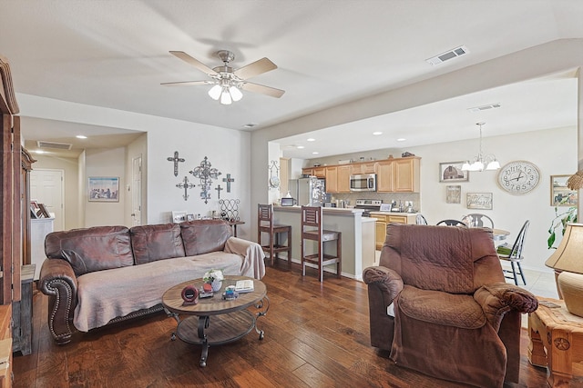 living room featuring ceiling fan with notable chandelier and dark hardwood / wood-style floors