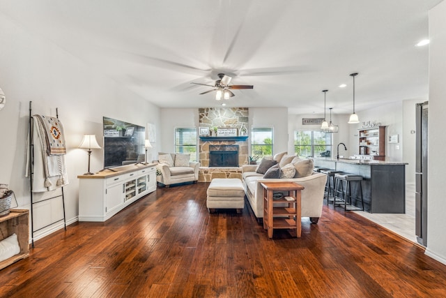 living room featuring sink, ceiling fan, dark hardwood / wood-style flooring, and a fireplace