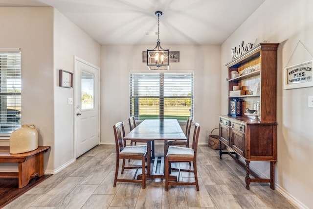 dining area with a wealth of natural light, light hardwood / wood-style flooring, and a notable chandelier