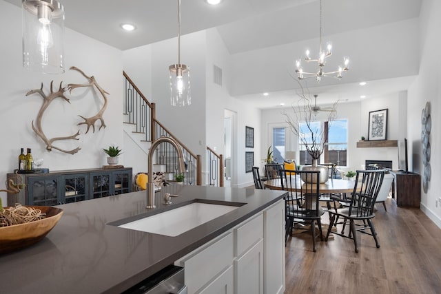 kitchen with sink, wood-type flooring, white cabinets, a chandelier, and hanging light fixtures