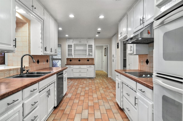 kitchen featuring white double oven, dishwasher, sink, black electric cooktop, and white cabinets