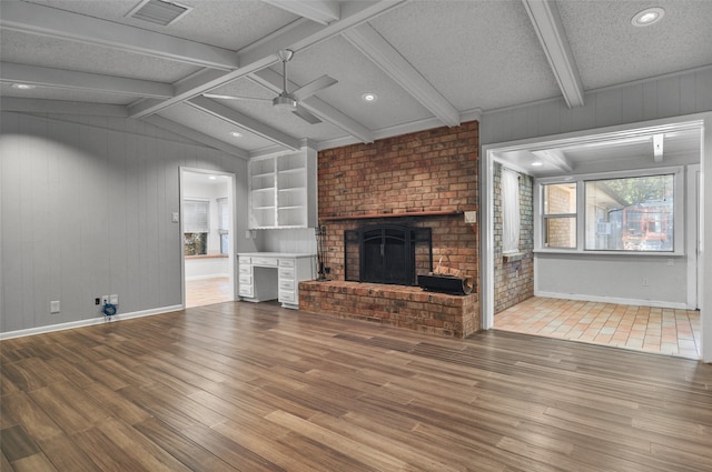 unfurnished living room with hardwood / wood-style flooring, a fireplace, ceiling fan, and a textured ceiling