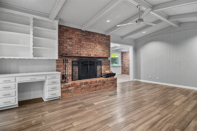 unfurnished living room featuring ceiling fan, light hardwood / wood-style flooring, lofted ceiling with beams, a textured ceiling, and a fireplace