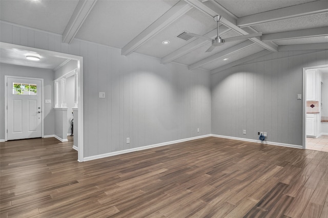 empty room with vaulted ceiling with beams, wood walls, and hardwood / wood-style floors