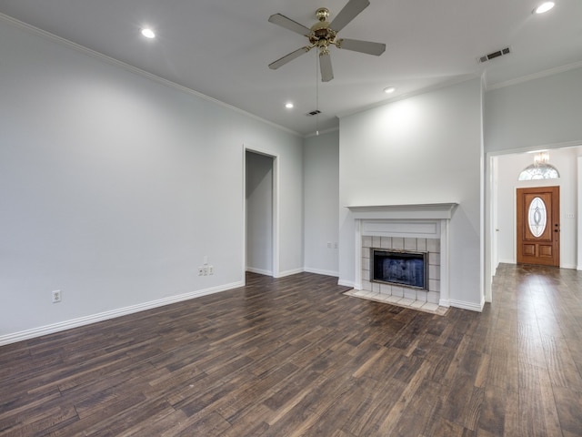 unfurnished living room featuring a tiled fireplace, crown molding, dark hardwood / wood-style floors, and ceiling fan