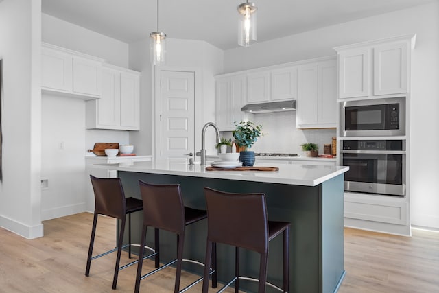 kitchen featuring white cabinets, stainless steel appliances, and an island with sink