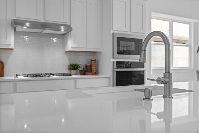 kitchen with decorative backsplash, white cabinetry, and stainless steel appliances