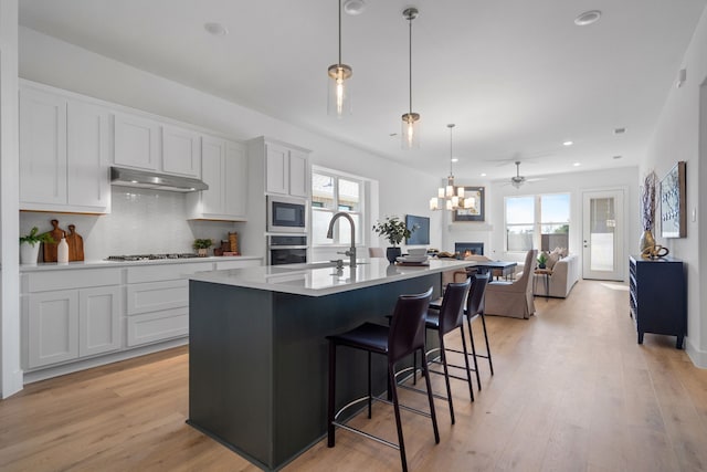 kitchen with a healthy amount of sunlight, white cabinetry, hanging light fixtures, and appliances with stainless steel finishes