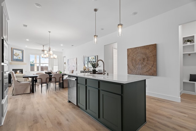 kitchen featuring pendant lighting, sink, a kitchen island with sink, and light hardwood / wood-style flooring