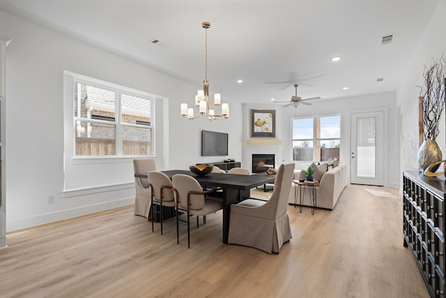 dining room with ceiling fan with notable chandelier and light hardwood / wood-style flooring