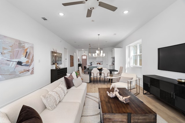 living room featuring light hardwood / wood-style floors and ceiling fan with notable chandelier