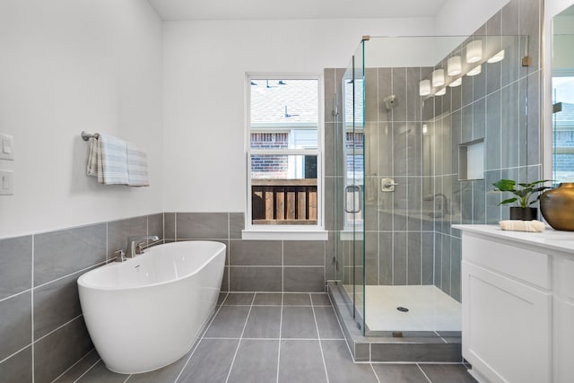 bathroom with tile patterned flooring, vanity, tile walls, and independent shower and bath