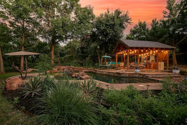 pool at dusk featuring a patio area and an outdoor structure